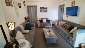 Ein Wohnzimmer mit zwei Sofas, einem Couchtisch und einem an der Wand befestigten Fernseher.