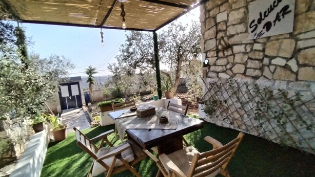 Eine Terrasse im Freien mit Steinmauer, Tisch und Stühlen sowie Topfpflanzen.