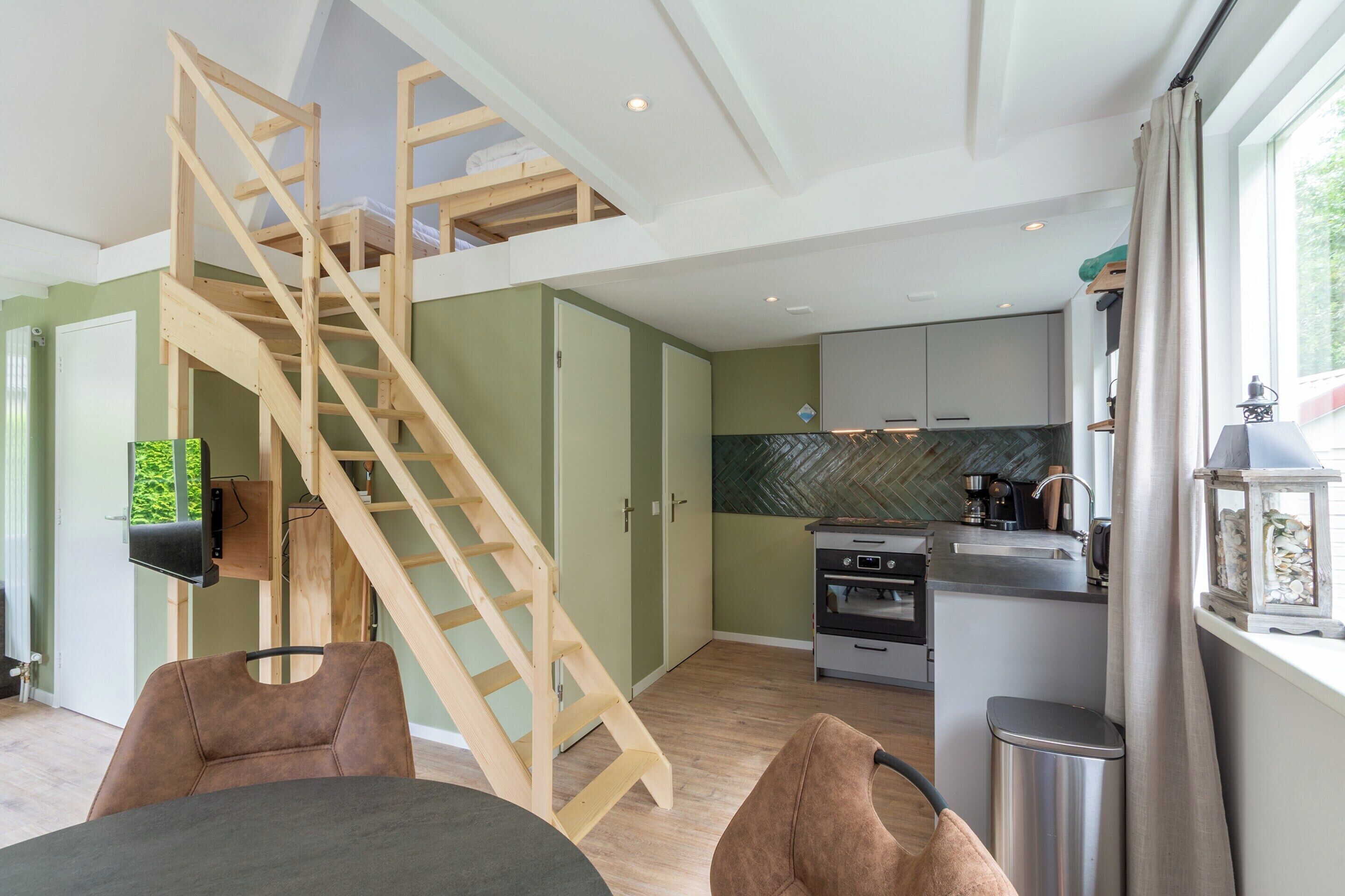 Une cuisine moderne avec des meubles en bois, un four encastré et une fenêtre donnant sur la verdure.