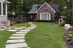 Una propiedad residencial con un camino pavimentado que conduce a una casa de ladrillo con un ventanal grande.