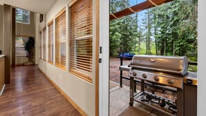 A modern kitchen with wooden blinds, a built-in grill, and a view of a forested area. - Evergreen House in heart Government Camp (Government Camp)