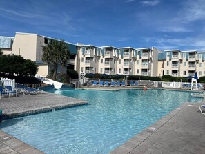 Une piscine avec des chaises longues et un poste de surveillance pour le sauveteur.