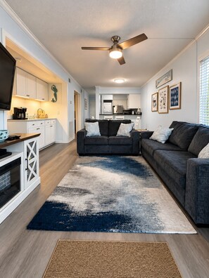 A modern living room with a dark grey sofa, a coffee table, and a large rug.