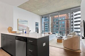 A modern kitchen with a dishwasher, a large window, and a view of a cityscape.