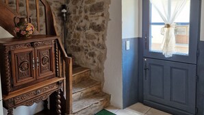 A rustic interior with a wooden staircase, stone walls, and a blue door with a white curtain. - Le Vieux Fusil. Gîte De Montagne (Freychenet)