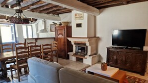 A living room with a fireplace, wooden furniture, a television, and a sign reading "Cours Gabriel FAURE." - Le Vieux Fusil. Gîte De Montagne (Freychenet)