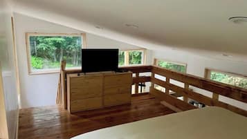 Un dormitorio con una cama de madera, un aparador y un televisor sobre un mueble.