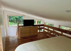 Un dormitorio con una cama de madera, un aparador y un televisor sobre un mueble.