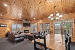L’intérieur d’une cabane en rondins, avec une cheminée, un plafond en bois et un coin repas.