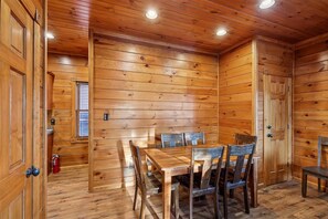 Un interior de madera con una mesa y sillas, paredes de madera y una puerta.