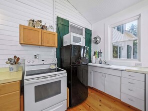 A kitchen with white cabinets, a black refrigerator, a stove, and a microwave.