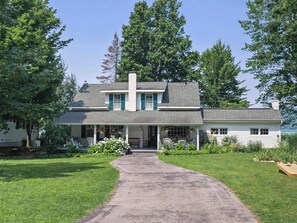A two-story house with a covered porch, a front yard, and a driveway leading to the entrance. - Seven Sisters On Little Glen (Empire)
