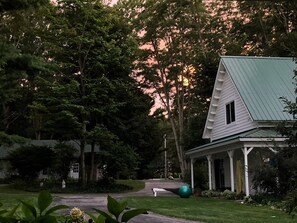 A house with a green roof, surrounded by trees and a well-maintained lawn.