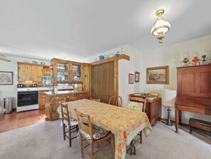 A kitchen with wooden cabinets, a dining table with chairs, and a chandelier. - Seven Sisters On Little Glen (Empire)