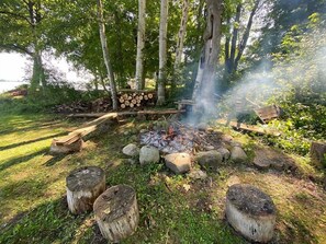 A campfire surrounded by rocks and logs in a forested area. - Seven Sisters On Little Glen (Empire)