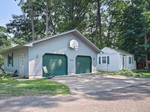 A two-story building with a garage, a basketball hoop, and a rocking chair outside.