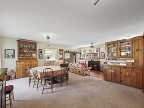 A spacious kitchen with wooden cabinets, a dining table, and chairs. - Seven Sisters On Little Glen (Empire)