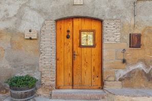 A wooden door with a small window, set in a stone wall with a brick base. - Casa Marco (Hoz y Costean)