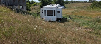 Serenity Lane Farm Stay: a trailer next to a barn full of farm animals
