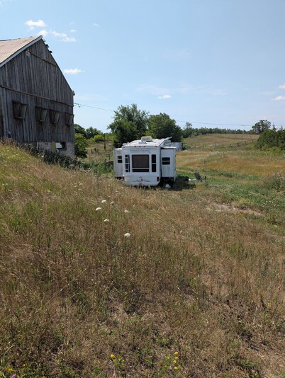 Serenity Lane Farm Stay: a trailer next to a barn full of farm animals