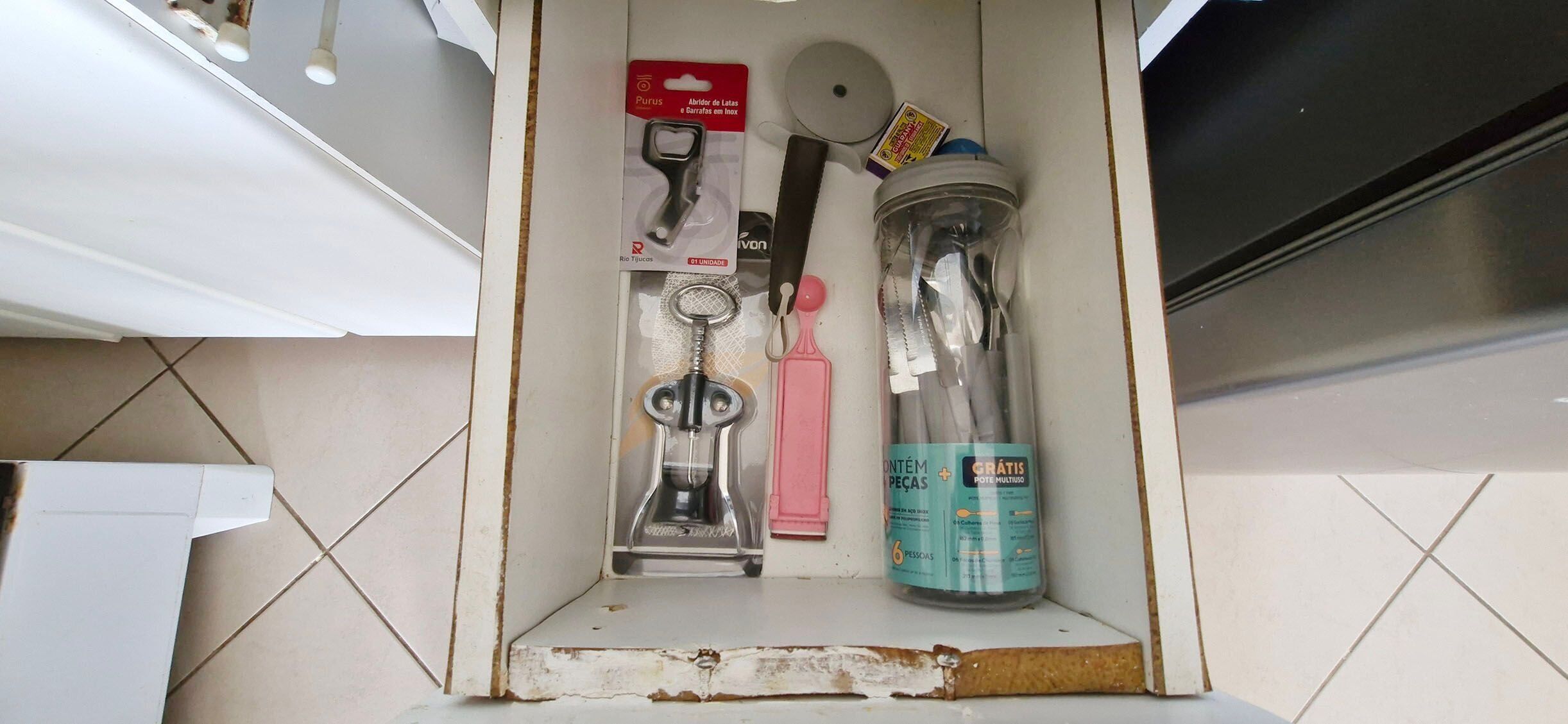 A kitchen drawer containing a can opener, a bottle opener, a corkscrew, a knife, and a jar opener.