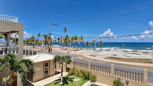 A coastal view with a beach, palm trees, and a small building.