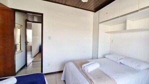 A bedroom with a bed, a wardrobe, and a door leading to another room.