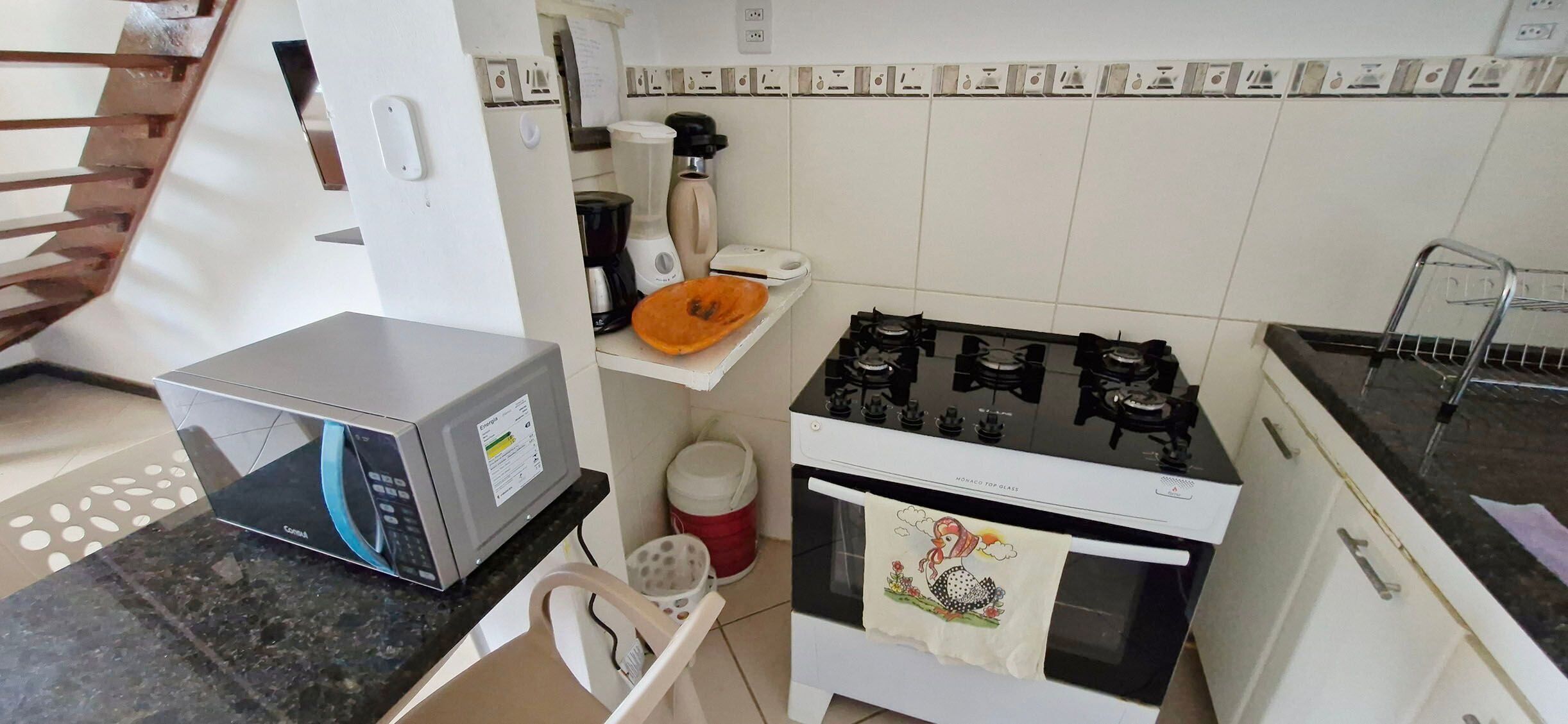 Una cocina equipada con microondas, estufa a gas y cafetera.