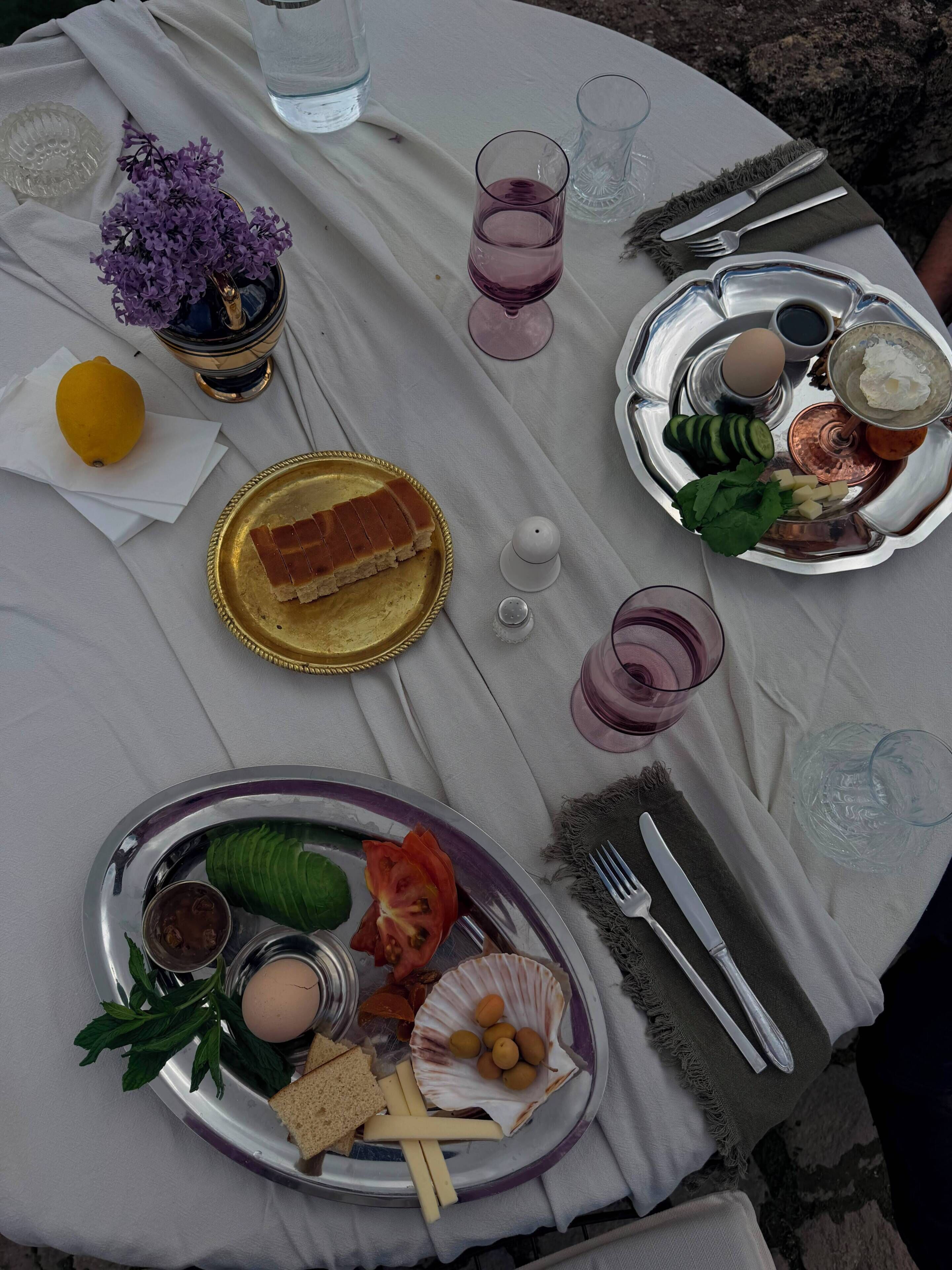 A table set with plates of food, glasses, and cutlery.
