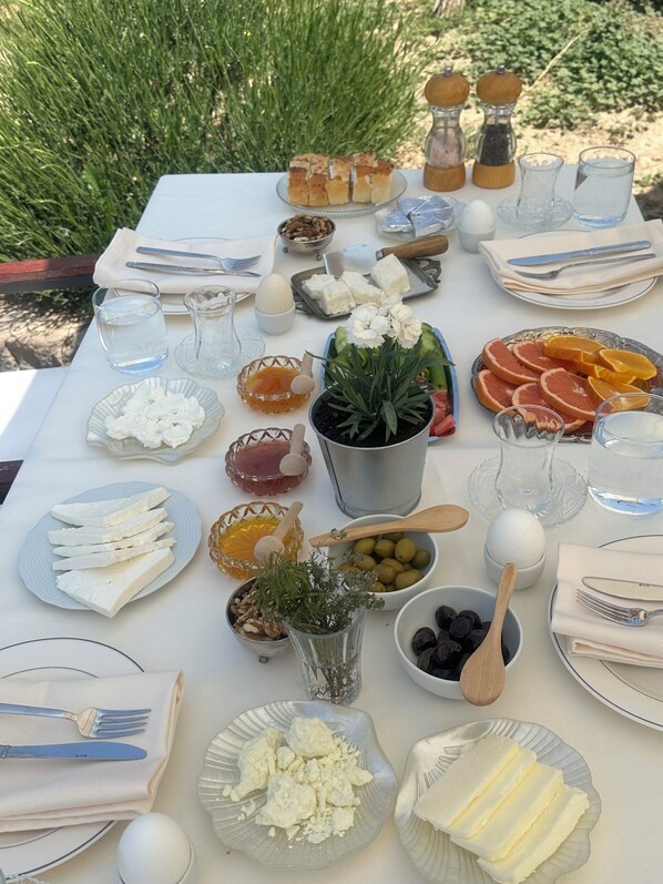 A table set with various food items, utensils, and a potted plant. - Hush Cappadocia (Urgup)