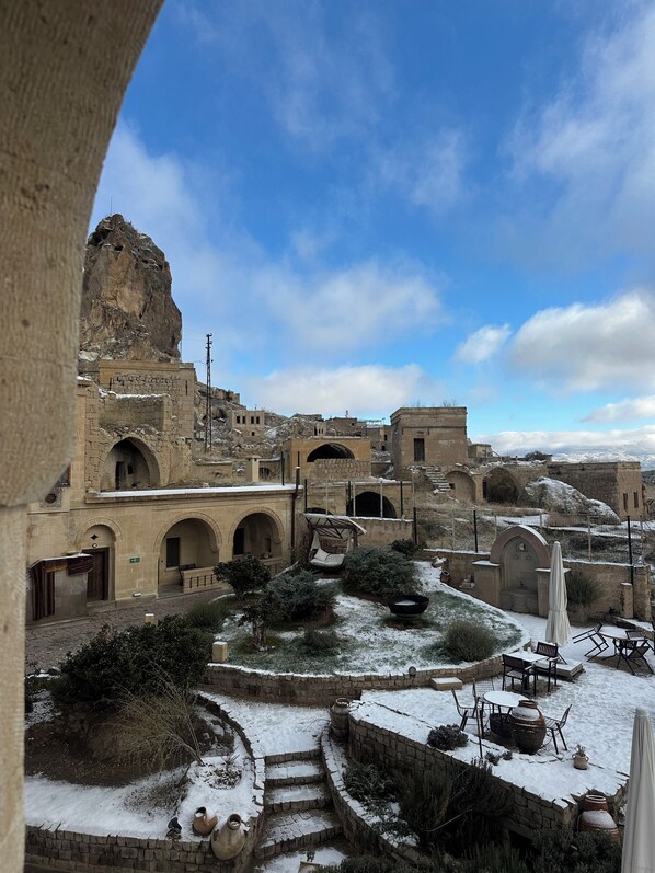 A courtyard with stone architecture, outdoor seating, and a view of the surrounding area. - Hush Cappadocia (Urgup)