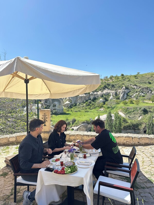 A table set outdoors with a tablecloth, plates, cutlery, and a bottle of water. - Hush Cappadocia (Urgup)