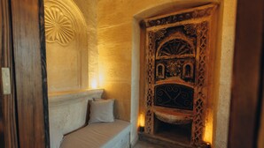 A room with a bed, a fireplace with intricate carvings, and a door with a decorative arch. - Hush Cappadocia (Urgup)