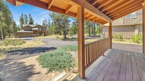 Une terrasse en bois dotée d’une rambarde, entourée d’un espace paysager agrémenté d’arbustes et d’arbres.