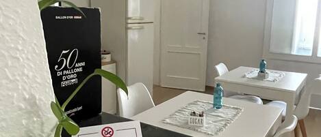 A clean, modern room with a dining area, a "NO SMOKING" sign, and a "50 ANNI DI PALLONE D'OR" sign.