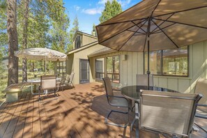 A wooden deck with outdoor furniture, including a table and chairs, and a large umbrella providing shade. - Updated, modern, in Sunriver, great space, no pets (Sunriver)