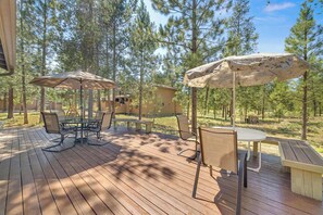 A wooden deck with outdoor furniture, including a table and chairs, and two large umbrellas. - Updated, modern, in Sunriver, great space, no pets (Sunriver)
