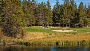 A golf course with a water body in the foreground, surrounded by dense trees. - Updated, modern, in Sunriver, great space, no pets (Sunriver)