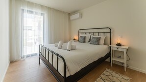 Een slaapkamer met een bed, nachtkastjes en een raam met gordijnen.