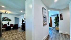 A modern interior with a dining area, kitchen, and a hallway leading to another room. - 4BR · Pool · Fenced Yard · Garage · Tree-Lined Street (Carmichael)