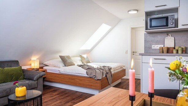 A modern bedroom with a loft bed, a small kitchenette, and a cozy seating area. - Zum Brandenburger Tor 18 (Damme)