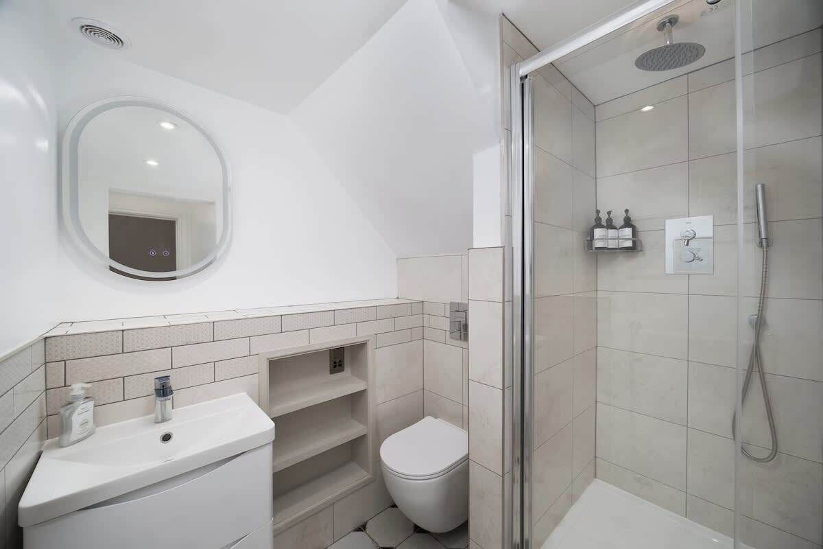 A modern bathroom with a glass shower enclosure, a white sink, and a toilet.