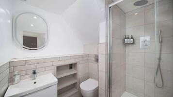 A modern bathroom with a glass shower enclosure, a white sink, and a toilet.