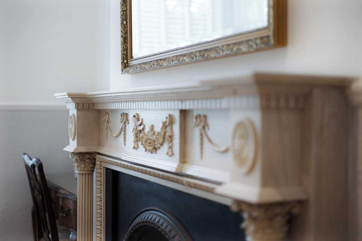 A fireplace with intricate carvings and a mirror above it.