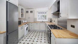 A modern kitchen with white cabinetry, a stainless steel refrigerator, a built-in oven, and a wooden countertop. - Stunning Apartment | Lincoln City Centre | Parking (Lincoln)