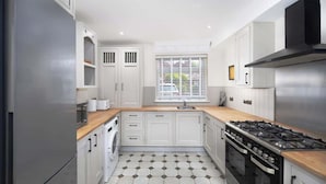 A modern kitchen with white cabinets, a stainless steel refrigerator, a gas stove, and a tiled floor. - Stunning Apartment | Lincoln City Centre | Parking (Lincoln)