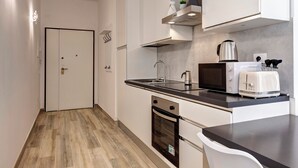 Una cocina compacta con microondas, tostadora y hervidor en la encimera, lavavajillas y dos puertas.