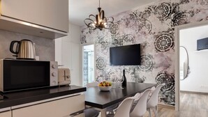 Una cocina moderna con un televisor de pantalla plana, un hervidor y un cuenco de fruta sobre la encimera.