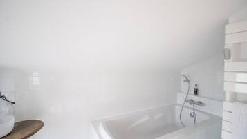 Une salle de bain moderne avec une baignoire, un banc en bois et un mur recouvert de carreaux blancs.