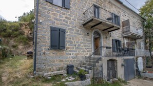 Un bâtiment en pierre doté d’un balcon, d’une porte et d’un petit jardin.